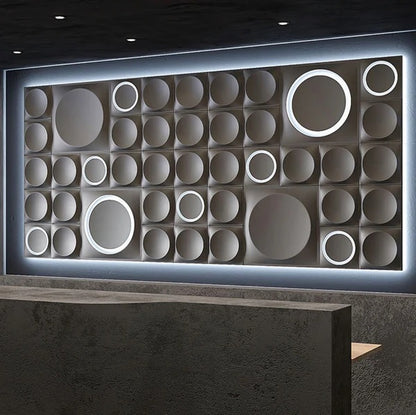 Dark gray geometric gypsum 3D wall panels with circular patterns and integrated LED lighting, creating a striking accent wall in a modern commercial space. These premium plaster 3D panels from Kandes, a Swiss producer of high-quality 3D wall panels, enhance interior design with perfect geometry, indirect lighting, and ambient illumination. Made from all-natural gypsum, A1 non-combustible, and eco-conscious, they provide seamless wall cladding for luxury interiors. Paintable for full customization.