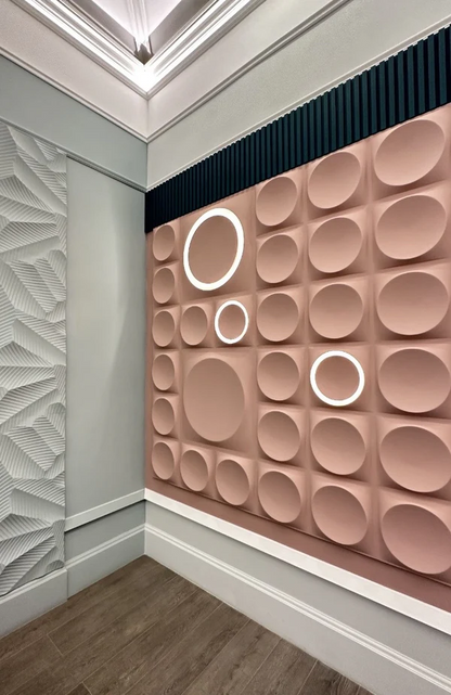 Blush pink geometric gypsum 3D wall panels with circular patterns and integrated LED lighting, creating a striking accent wall in a modern commercial space. These premium plaster 3D panels from Kandes, a Swiss producer of high-quality 3D wall panels, enhance interior design with perfect geometry, indirect lighting, and ambient illumination. Made from all-natural gypsum, A1 non-combustible, and eco-conscious, they provide seamless wall cladding for luxury interiors. Paintable for full customization.